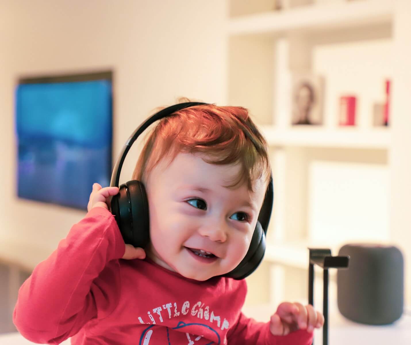 toddler with fair skin excitedly listening to sound through a black headset
